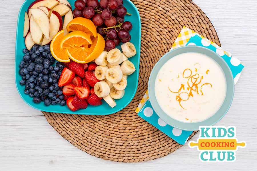 orange dip in a bowl with a plate of fresh fruit on a table