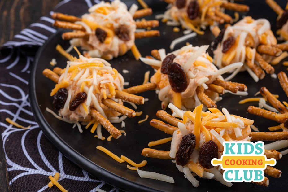 spiders made of cream cheese and shredded cheese with pretzels for legs and raisins for the eyes. Logo: Kids Cooking Club
