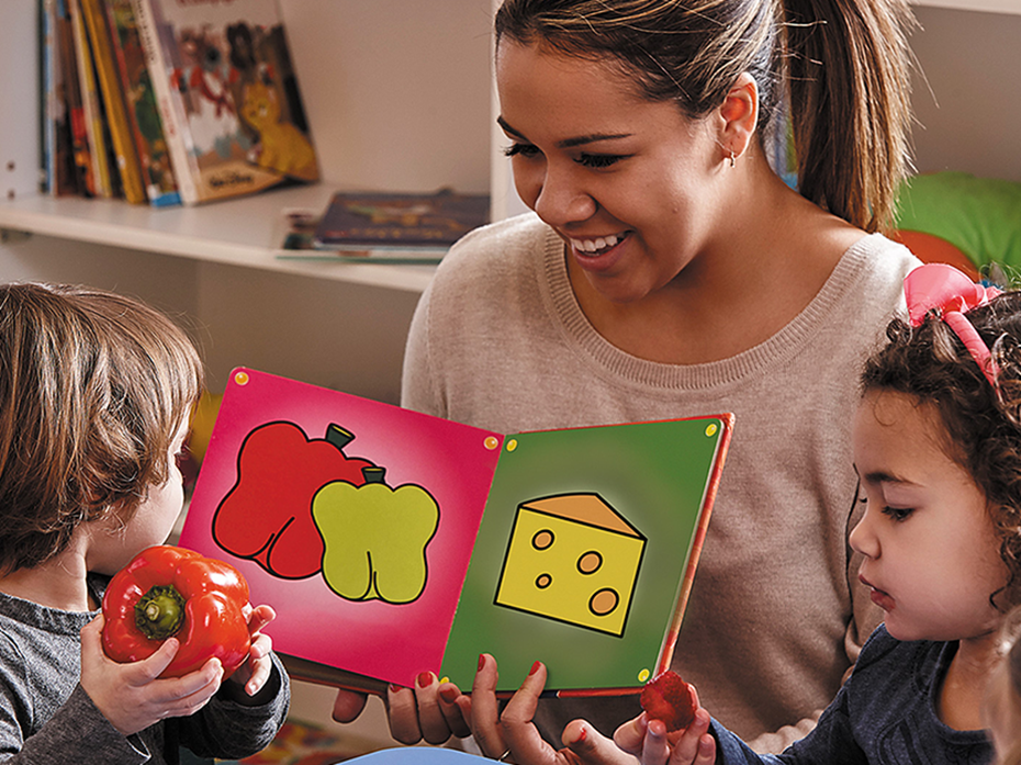 An educator that is reading a book with kids