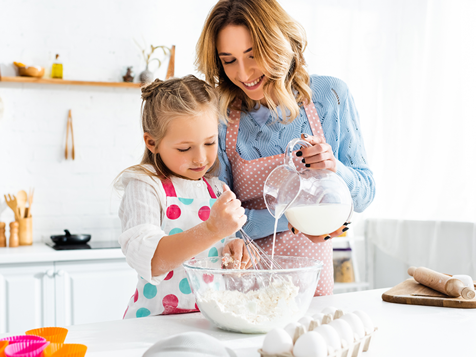 An adult cooking with a little girl